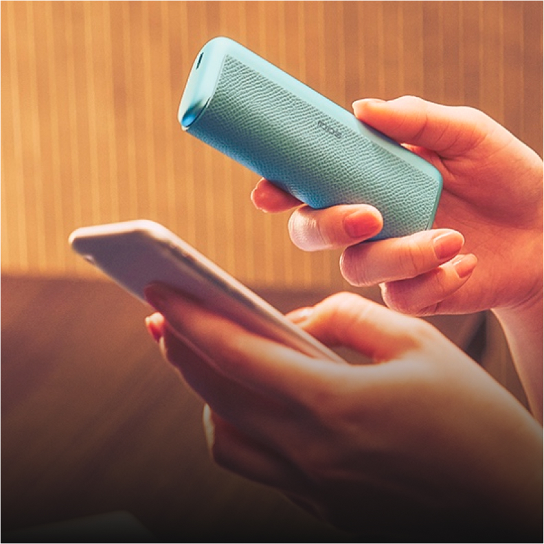 Person hält Smartphone und IQOS Kit in der Hand.